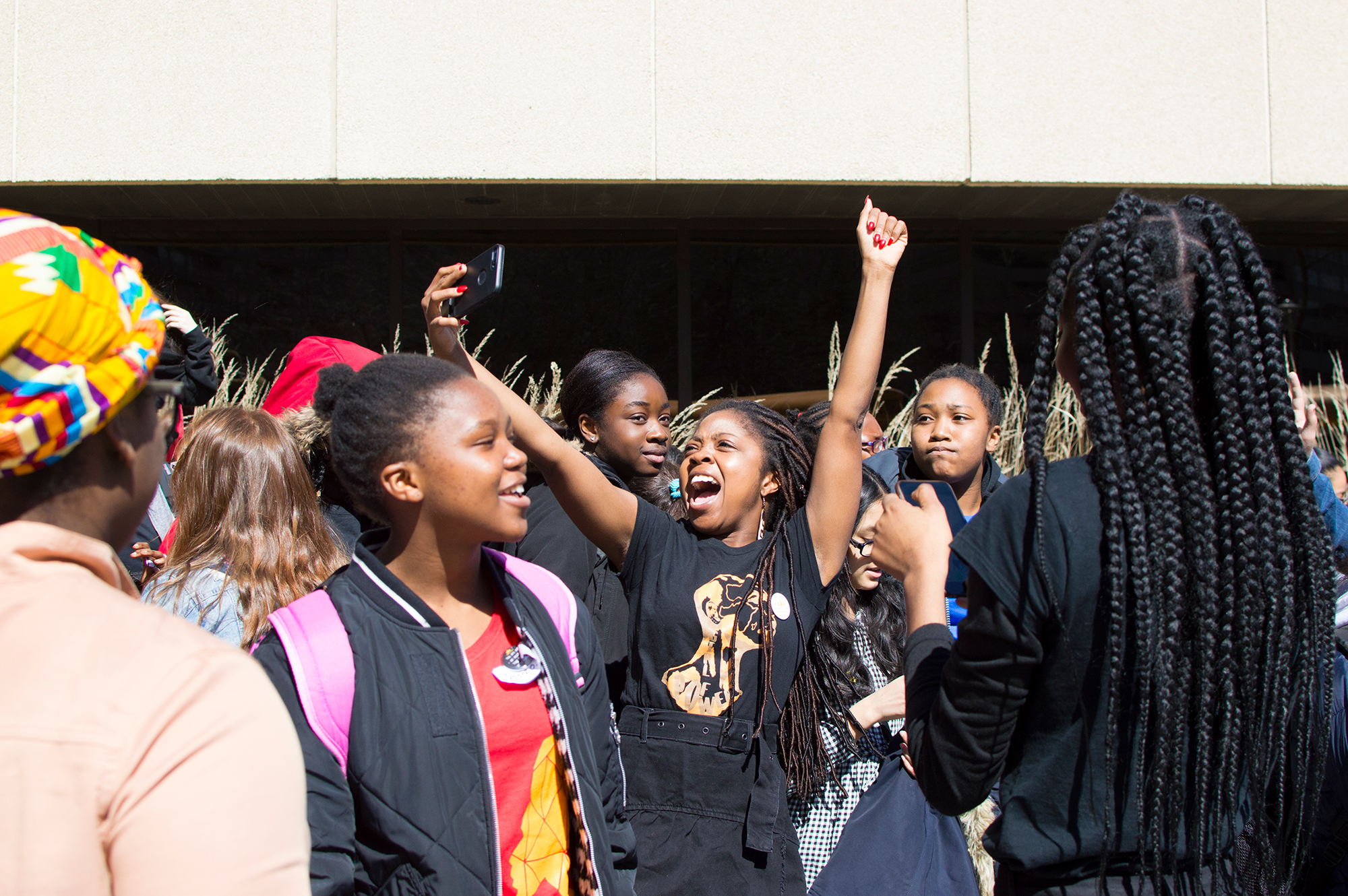 Founder Aisha Addo cheering with hands in the air and young Black girls surrounding her outside