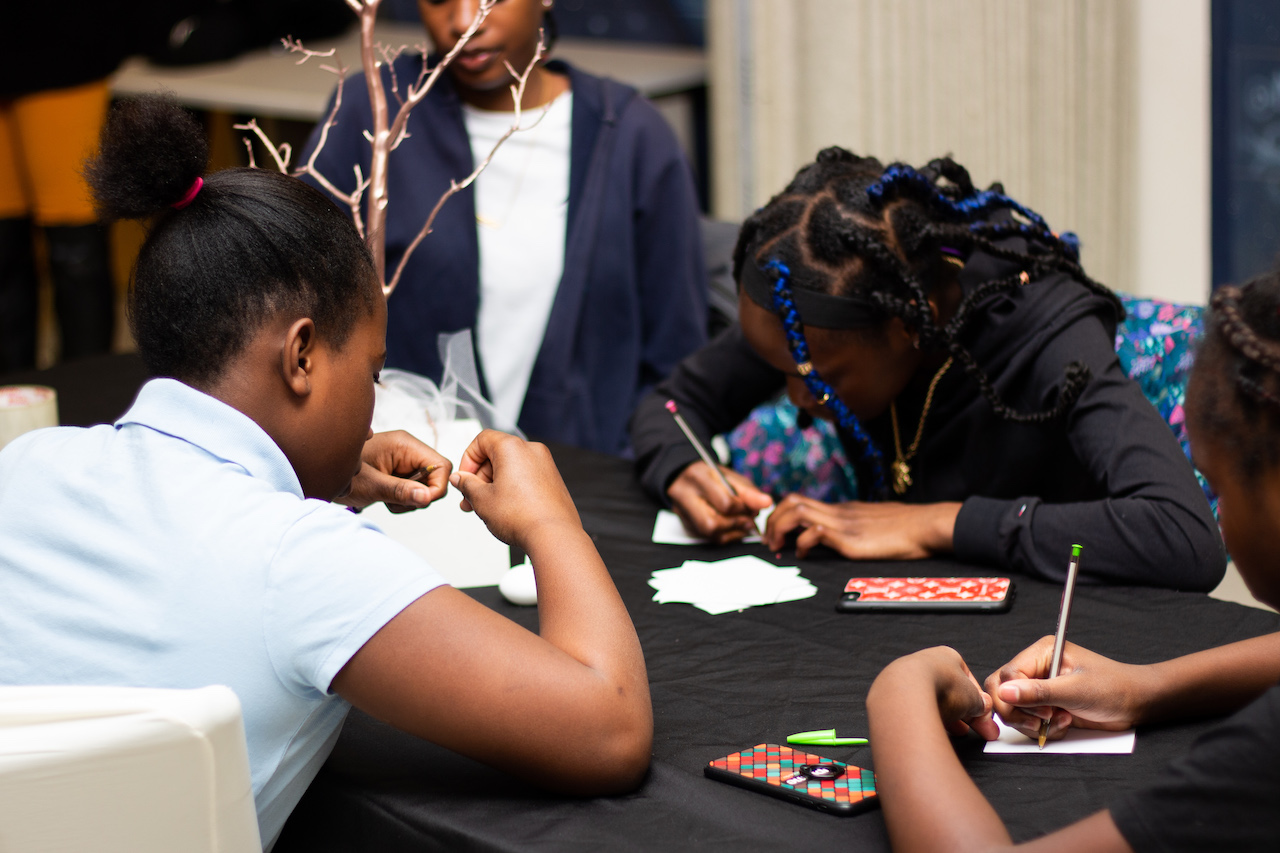 Young Black girls at table writing on paper