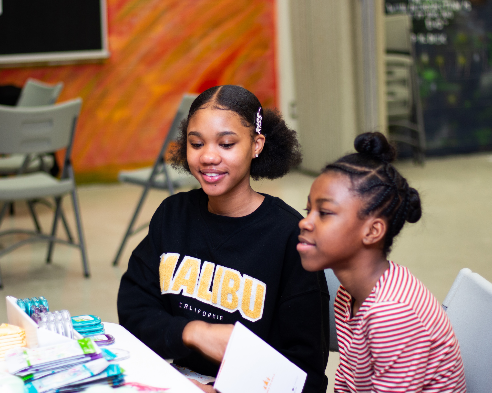 Two young Black girls sitting at a table at a Power to Girls program event