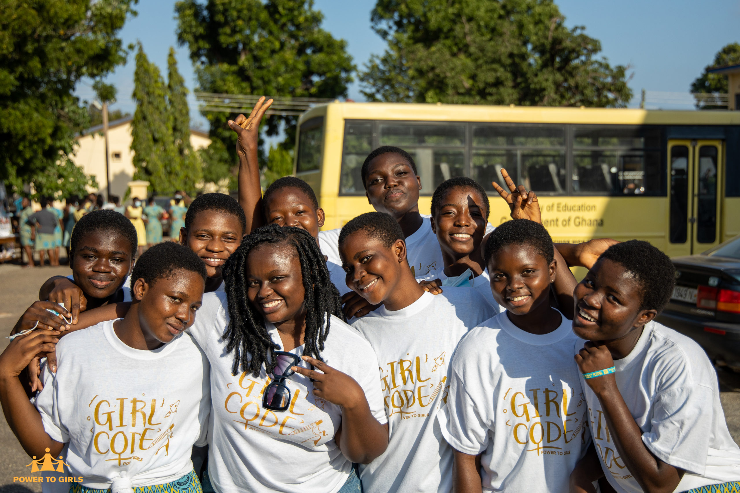 Group of young Black girls posing in front of a bus in Ghana wearing Girl Code t-shirts